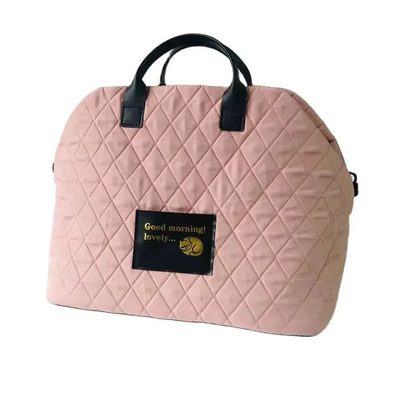 A light pink quilted portable soft-sided pet carrier for cats and small dogs.