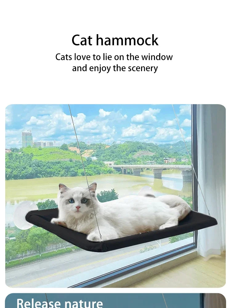 A white cat is relaxing on a black window hammock, enjoying the scenic view outside.