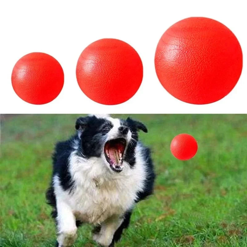 Three bright red rubber dog balls are shown against a green outdoor background with a dog in the foreground.