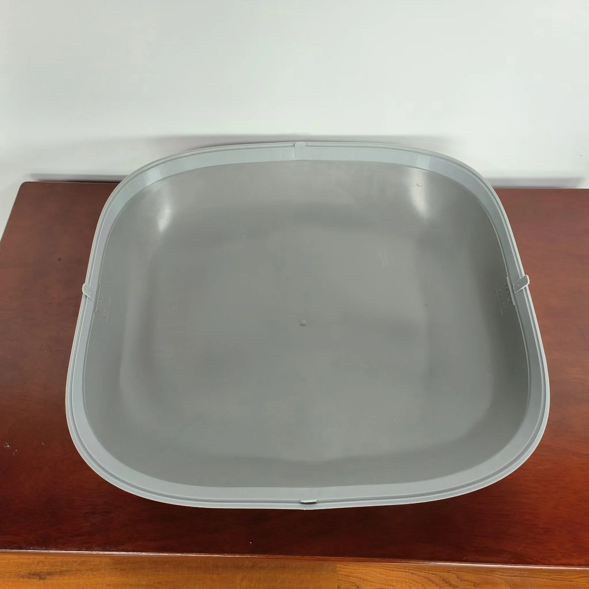 A gray silicone litter-trap mat designed for automatic cat litter boxes, resting on a wooden surface.