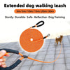 Orange extended dog walking leash coiled on a gray surface with a hand holding the strap.