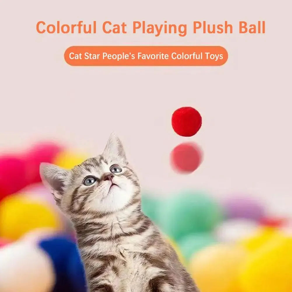 A tabby kitten looks up at a red plush ball toy.
