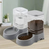 A clear plastic pet food bowl and water dispenser with a separate compartment for dry food, sitting on a wooden surface.