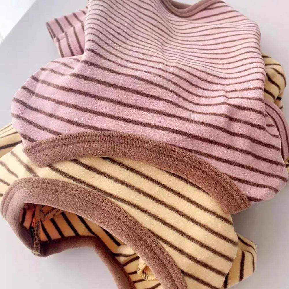 A stack of cozy striped dog pajamas in pink and beige tones.