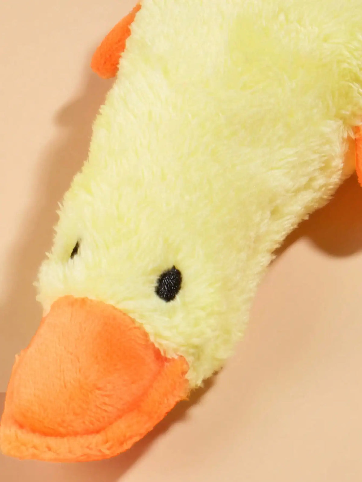 A yellow plush toy shaped like a duck with an orange beak and black eyes.