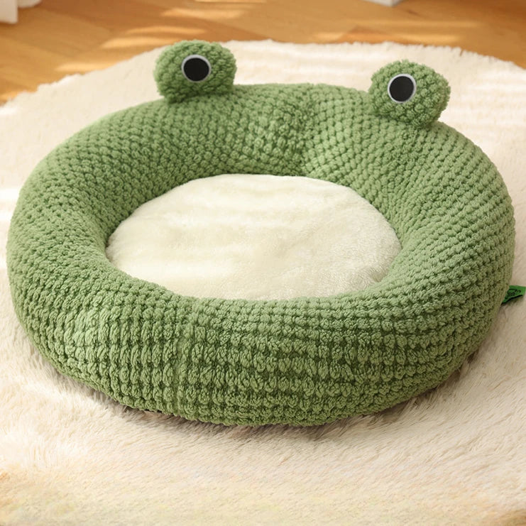 Nido de mascota de peluche de ganchillo verde con forma de rana y ojos grandes, interior blanco.