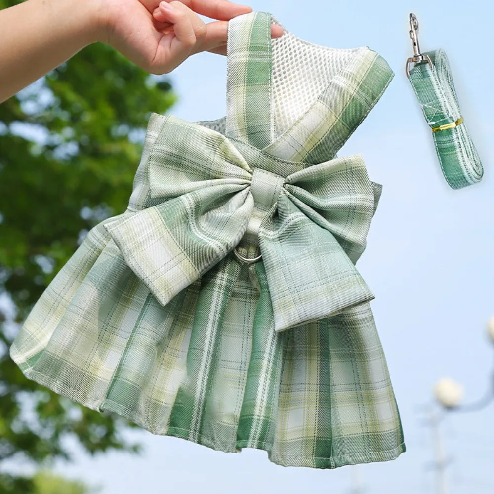 A green plaid reusable dog harness dress being held by a hand outdoors.
