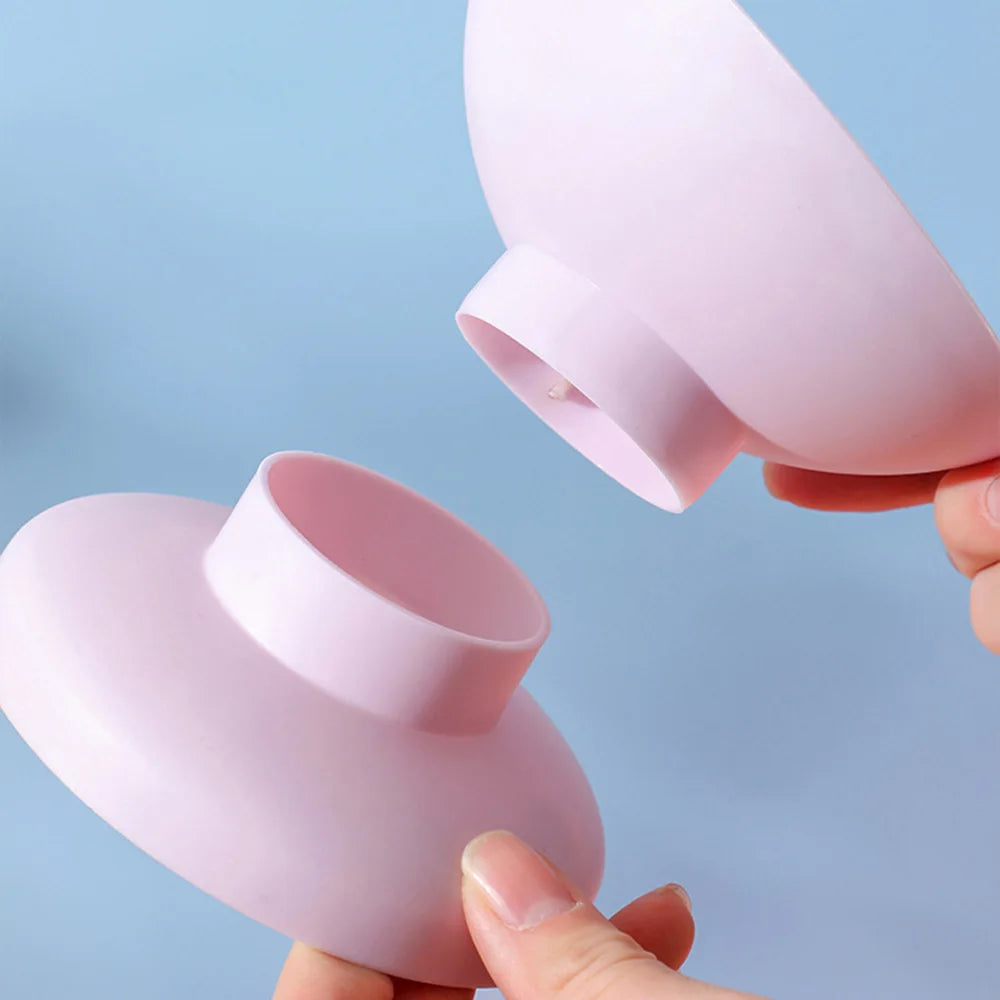 A pink macaron elevated anti-spill bowl with a non-slip base being held by a hand.