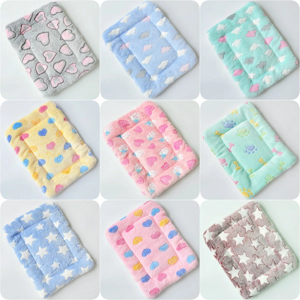 A collection of various plush fleece pet blankets and mats in pastel colors like pink, blue, and green.