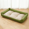 A rectangular, olive green corduroy sofa bed for pets is lying on a light wooden floor.
