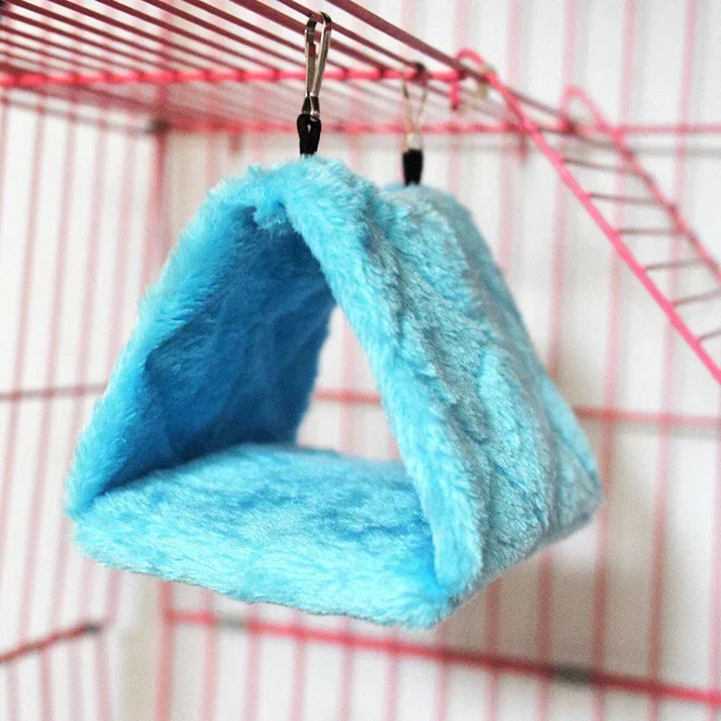 A bright blue plush bird hammock nest hanging from a wire cage