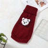 A deep red knitted sweater with a white bear design for a small to medium dog is displayed on a white surface.