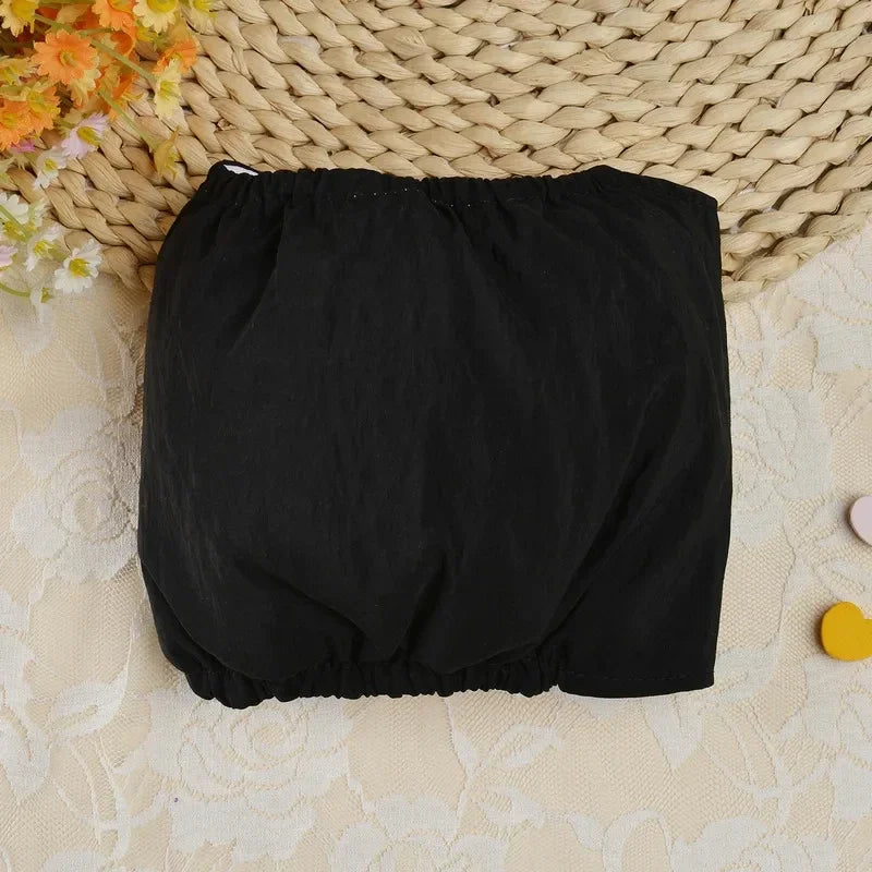 Couches réutilisables pour chiens noires avec ajustement, posées sur un tapis tissé.