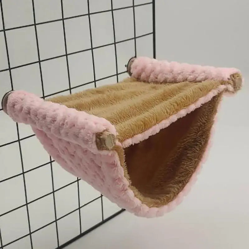 Gemütliches Kuscheltier-Hängematte mit rosa und beige Sherpa-Futter vor schwarzem Gitterhintergrund.