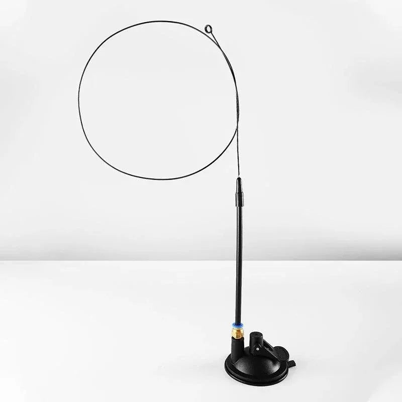 A black interactive chirping bird cat toy with a circular head and a long wire extending from it.