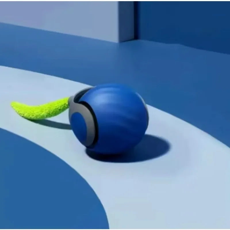 Blaues rollendes Spielzeug mit grünem Kunstfellschwanz auf einer glatten, gewölbten Oberfläche.