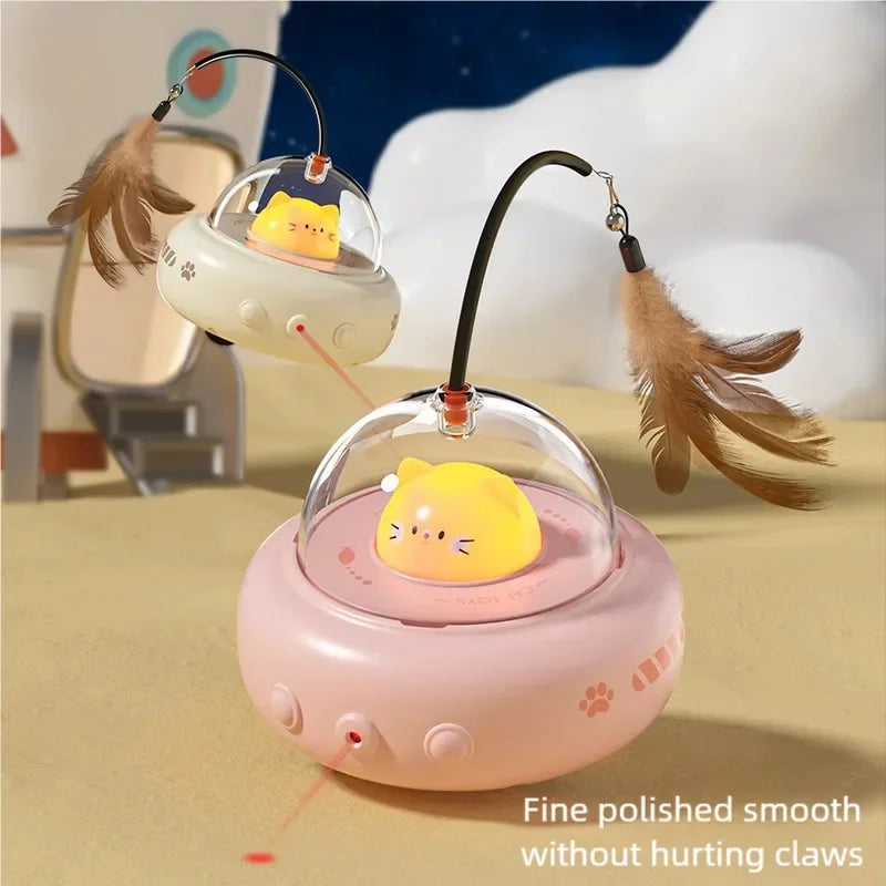A pink automatic UFO cat teaser toy with a yellow cat head and a detachable feather wand is displayed on a light surface.