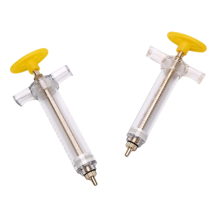 A yellow parrot feeding syringe with a clear plastic hose and a metal tip.