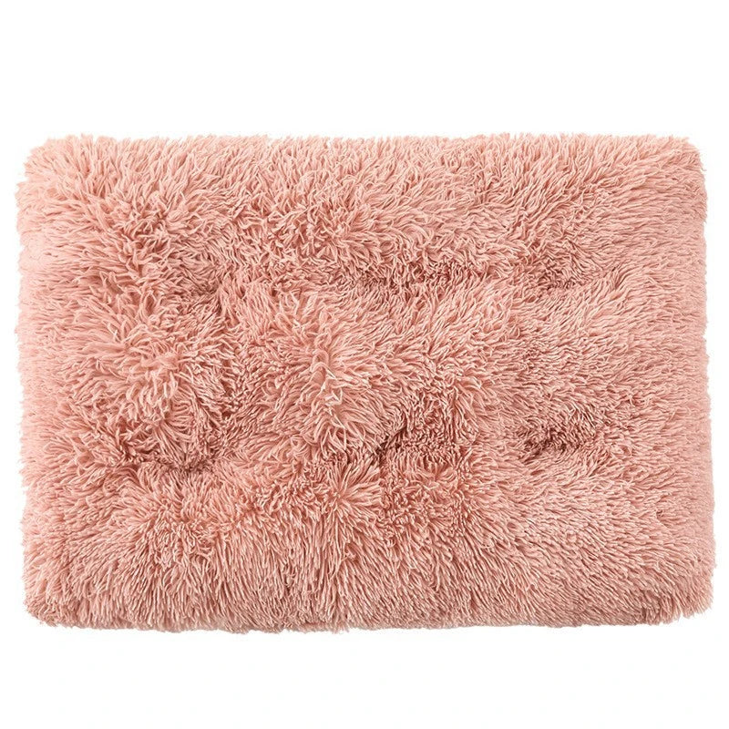 A square, fluffy, light pink pet bed mat with a non-slip texture.