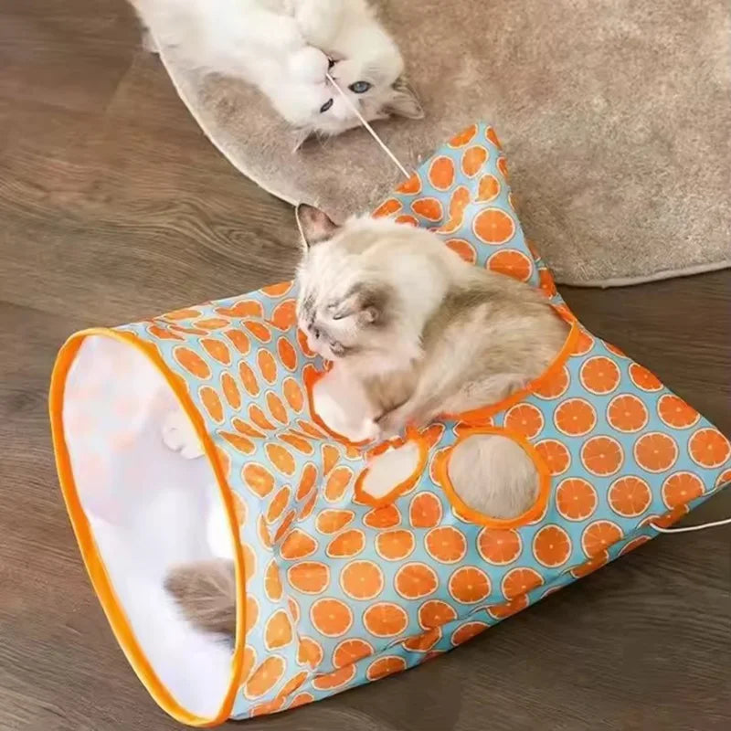 A fluffy cat is playing inside an orange and blue crinkle tunnel designed as an interactive hideout for cats.