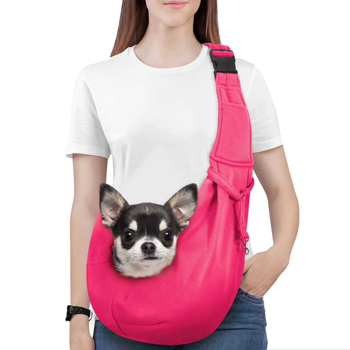 A woman is holding a bright pink reversible hands-free dog sling carrier with a small dog inside.