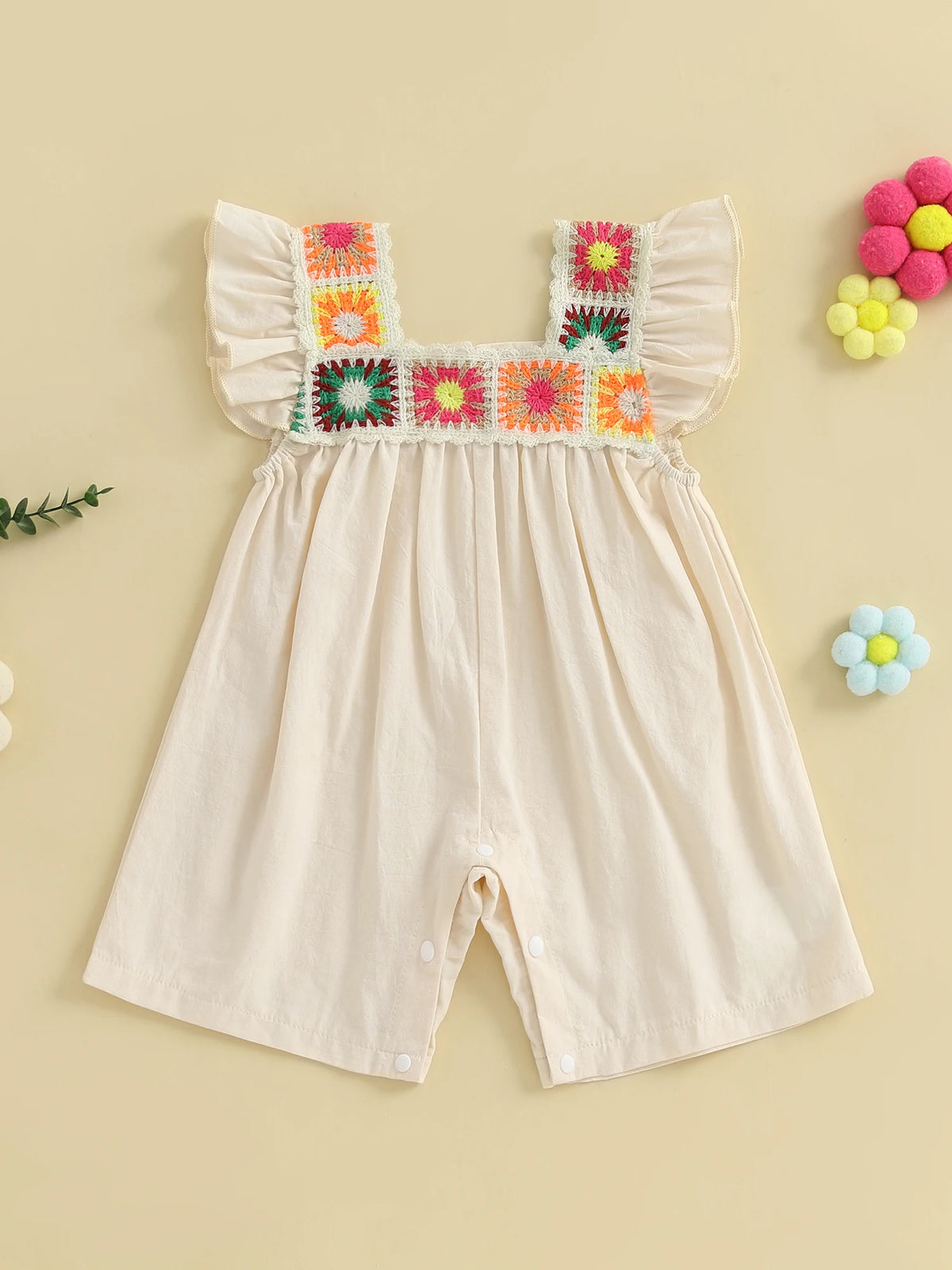 A light pink toddler romper featuring floral embroidery trim on the neckline and cuffs.