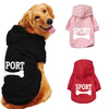 A dog wearing a black fleece hoodie with white bone print, alongside pink and red sport hoodies.