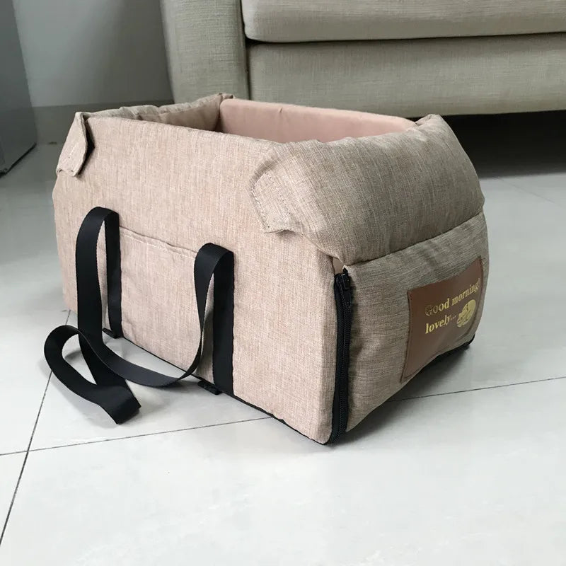 Beige tragendes Hundesitzbett mit schwarzen Gurten und Leder-Tag auf hellem Boden.