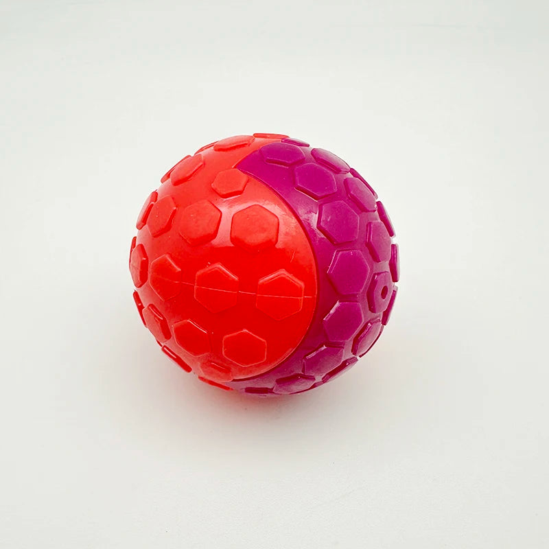 A bright red and purple squeaky rubber play ball toy for dogs.