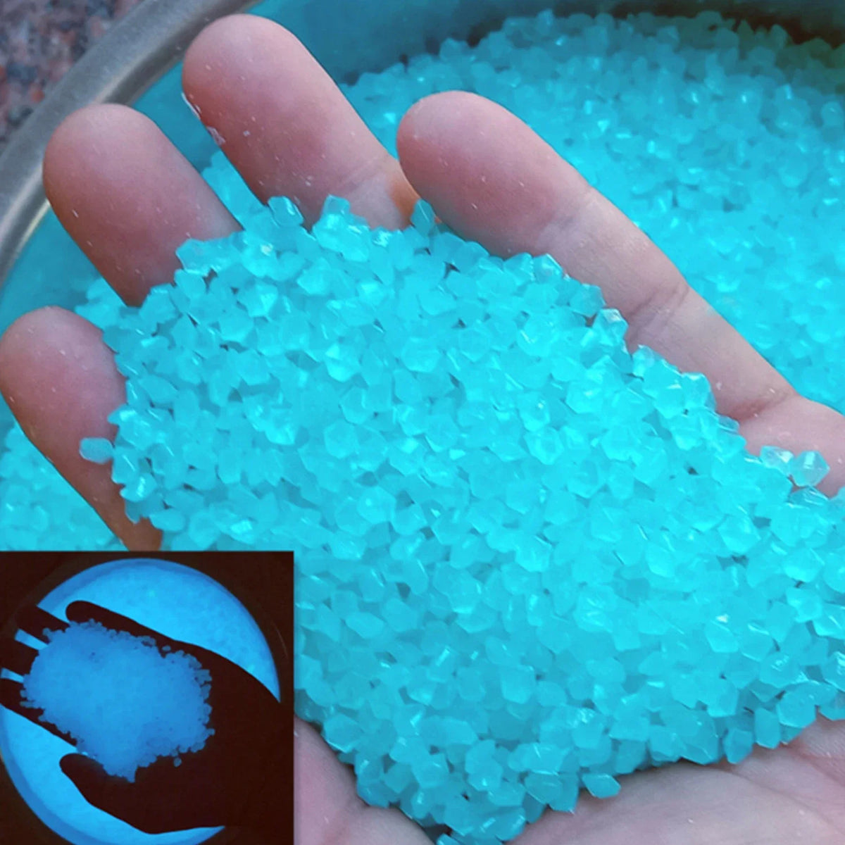 A hand holds a pile of glowing blue glow-in-the-dark decorative resin pebbles.