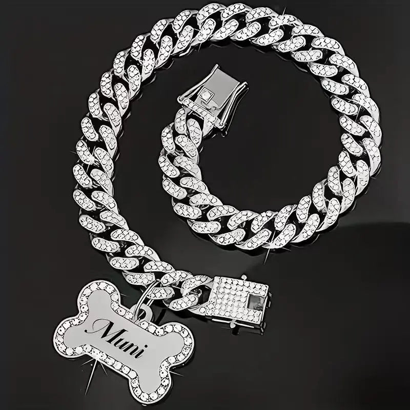 A silver-toned Cuban link rhinestone pet collar with a bone charm is displayed against a black background.