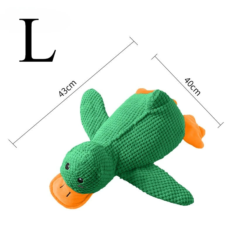 A green plush duck dog toy with an orange beak and ear, shown next to a letter L for scale.