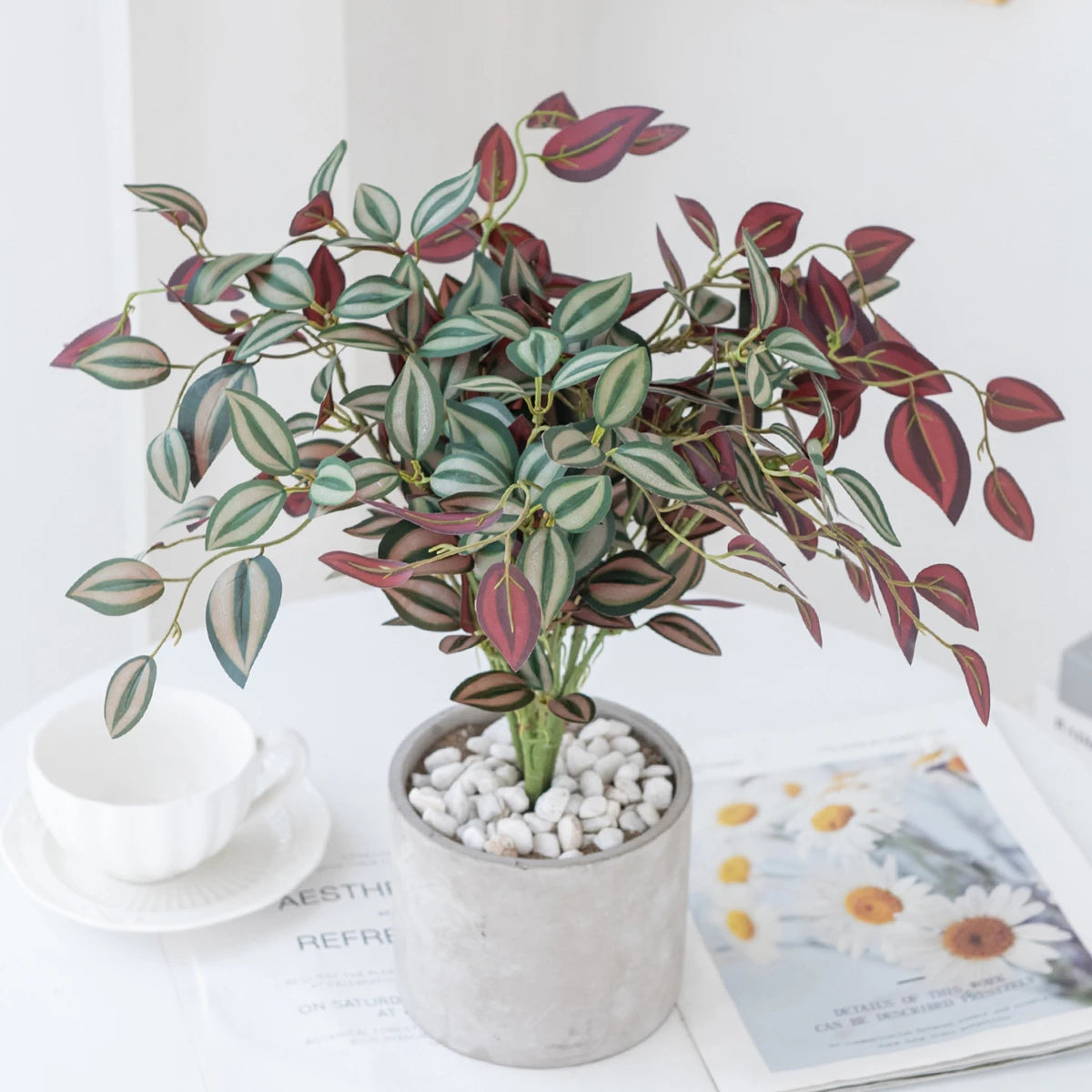 Artificial bonsai tree with green and reddish leaves potted in a gray ceramic container
