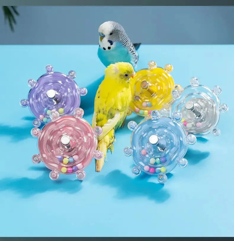 Eine Sammlung farbenfroher, rotierender Futterspender für Papageien, darunter violette, gelbe und klare Glasschalen.