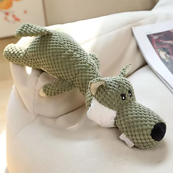 A handmade green plush dog toy resembling a squirrel or small canine is resting on a white surface.