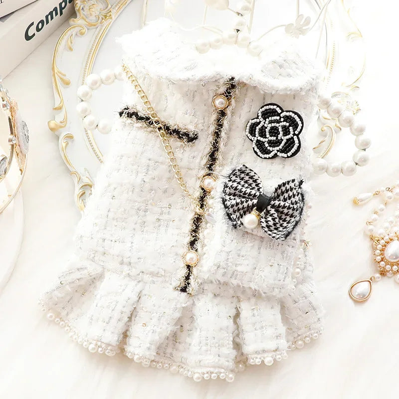 Robe tricotée blanche avec bordure de dentelle et détails de perles sur fond clair.