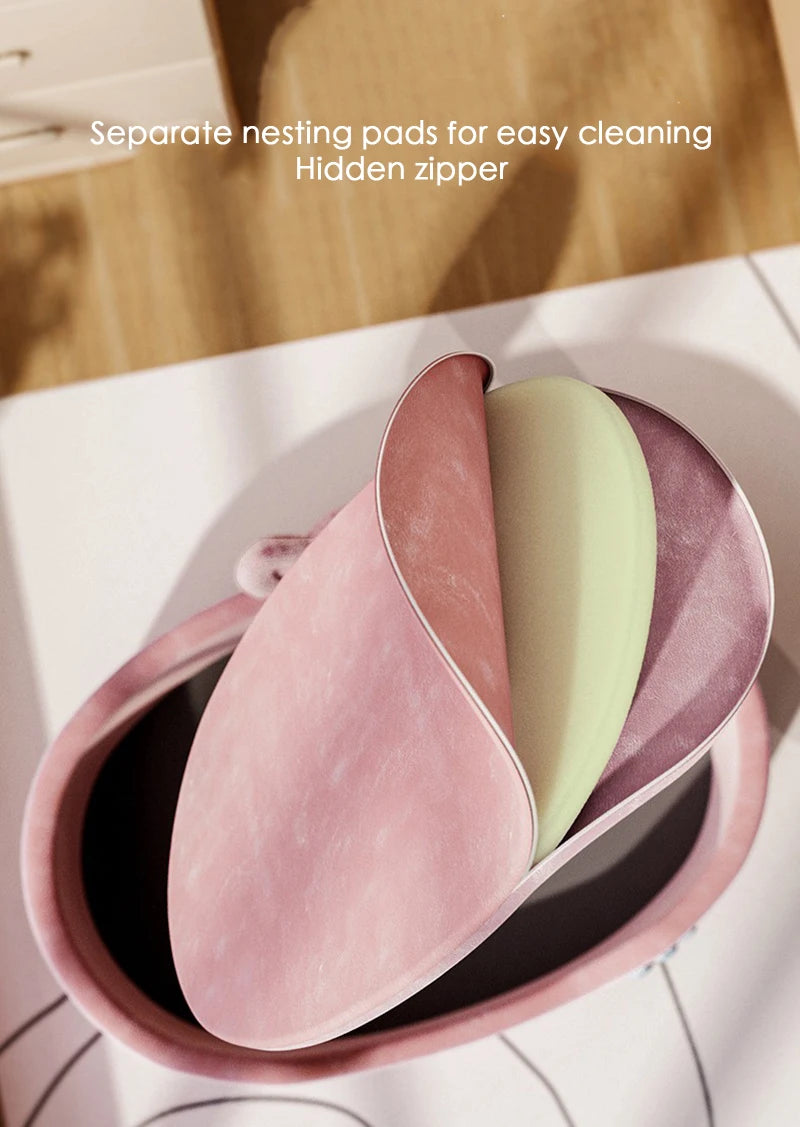 A pink and light green cozy plush pet bed with a removable cover shown in a shallow dish.