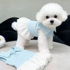 Un perro blanco y esponjoso vistiendo un vestido polo a rayas azul claro y pantalones a juego.