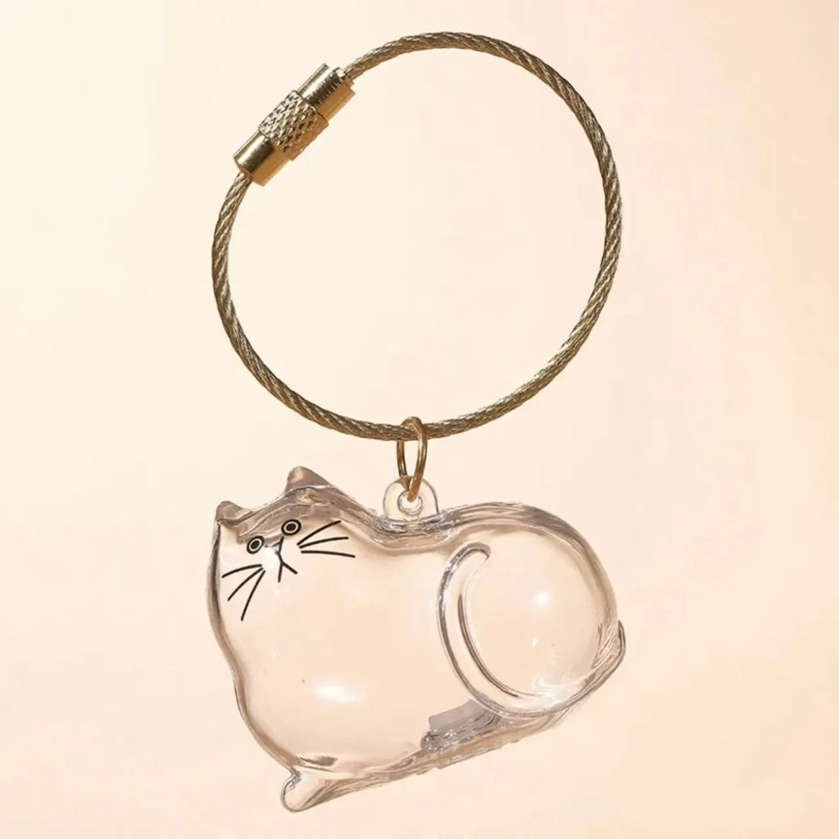 A clear glass charm shaped like a cat is suspended from a braided gold-colored cord with a metal clasp.