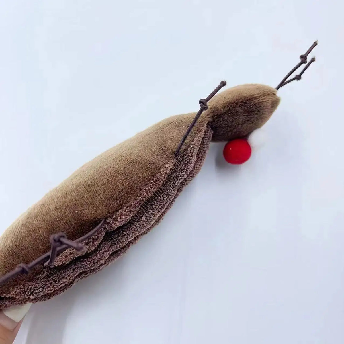 A plush cockroach cat toy with catnip, brown and reddish-brown, lying on a white background.