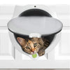 A gray tabby cat is peering out of a white pet door flap installed in a white cabinet.
