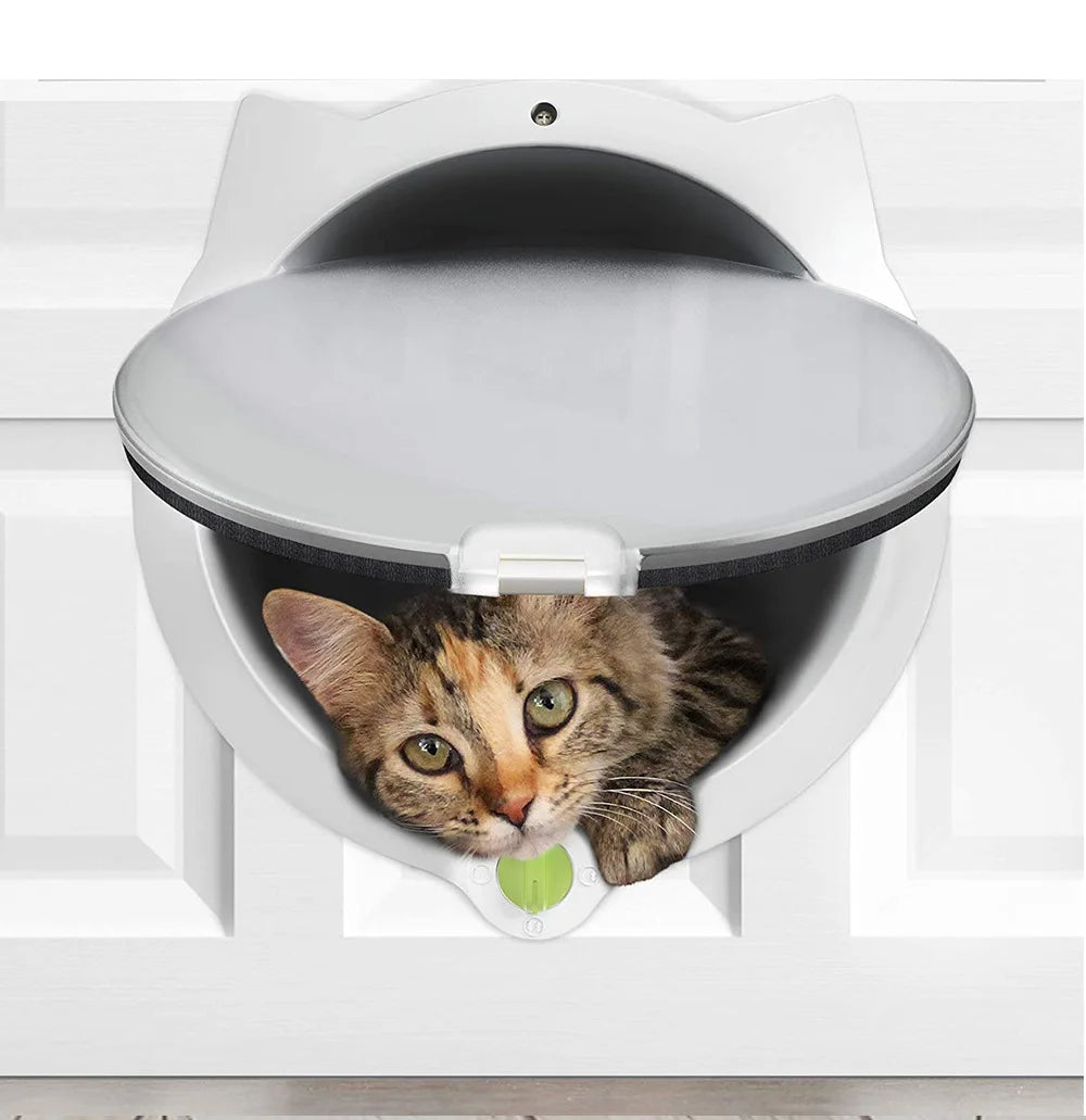 A gray tabby cat is peering out of a white pet door flap installed in a white cabinet.