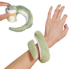 A hand holds a soft, bendable green snake plush toy with white accents.