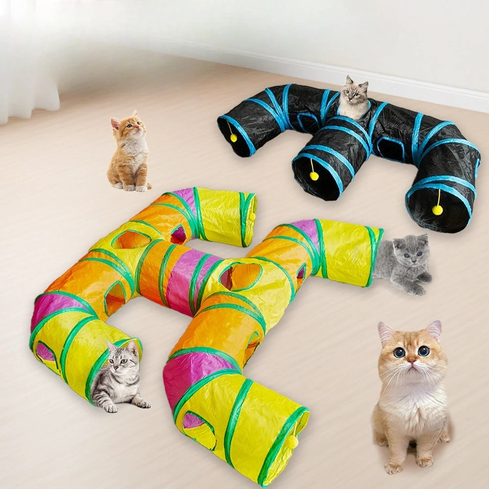 A colorful, flexible rainbow cat tunnel with multiple entrances is shown lying on a light floor with several cats interacting