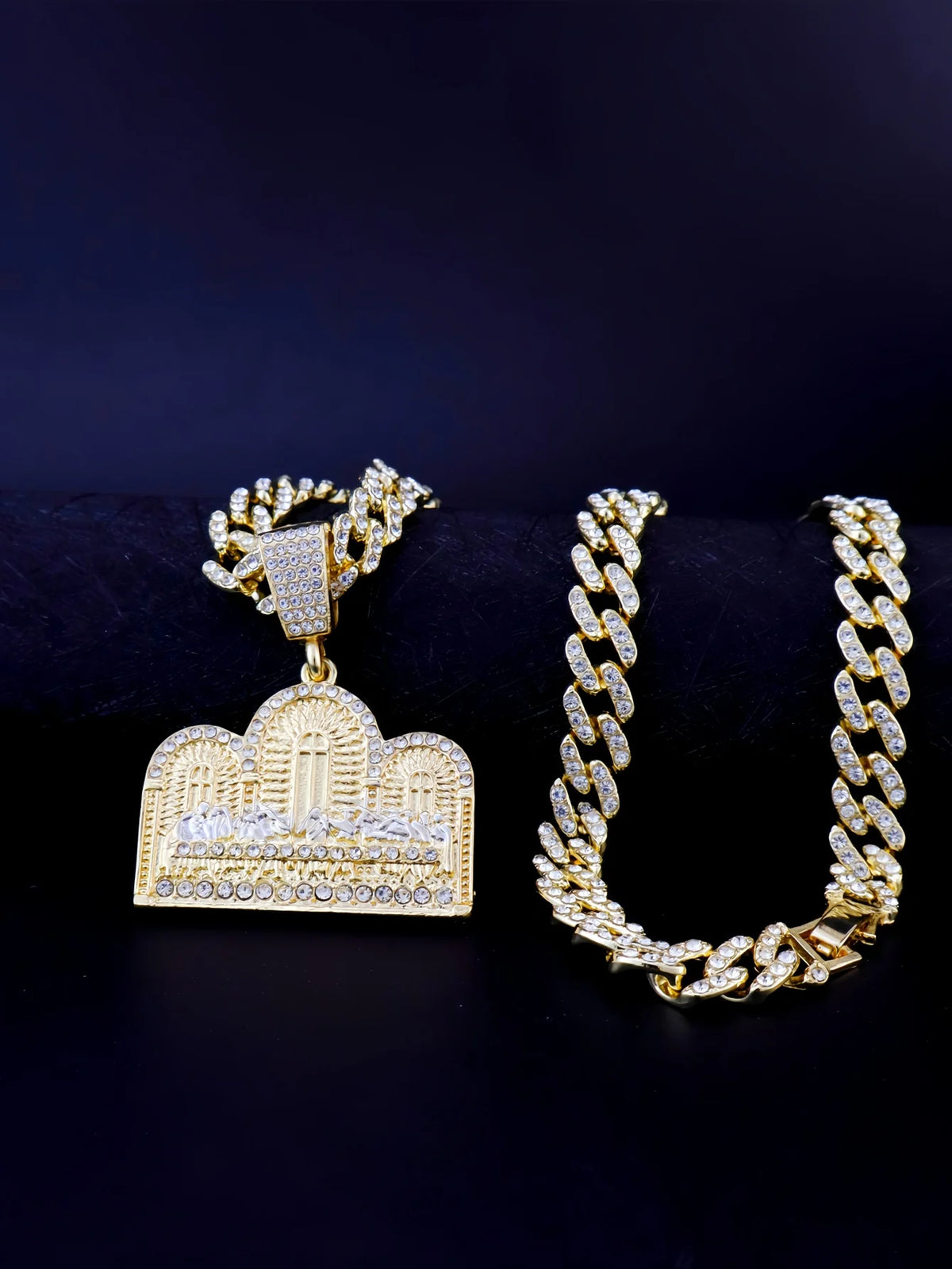 A gold plated last supper medallion pendant and a matching Cuban chain necklace displayed against a dark background.