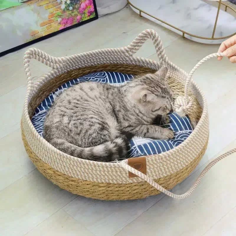 A gray tabby cat is relaxing inside a woven rattan cat bed with a blue and white cushion.
