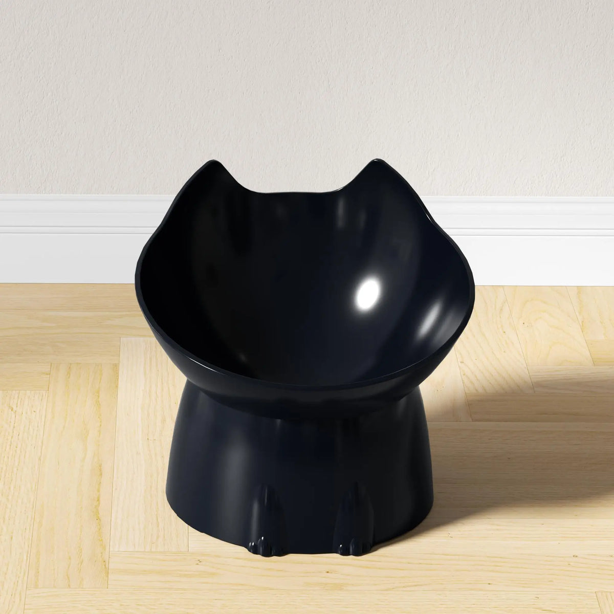 A black elevated cat bowl with a storage feature and anti-tip base sitting on a light wooden floor.