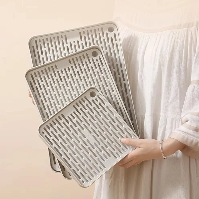 A hand holds a stack of gray universal pet litter boxes for small animals.