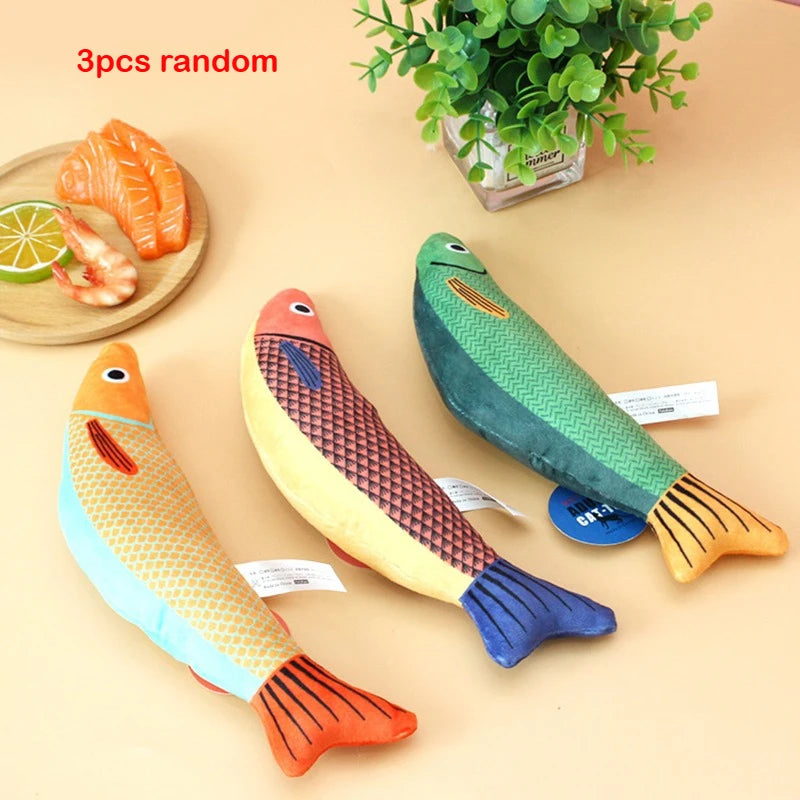Three random interactive catnip fish toys, including a goldfish shape and a salmon shrimp shape, are displayed on a light bac