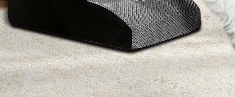 A black memory foam pet ramp with a gray cover is placed on a light-colored carpet.